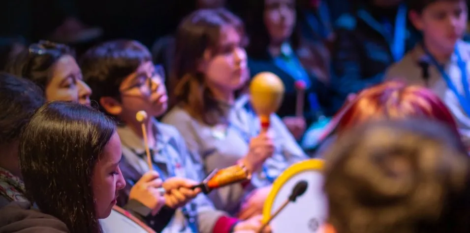 Estudiantes participando con instrumentos de mano durante una actividad educativa.